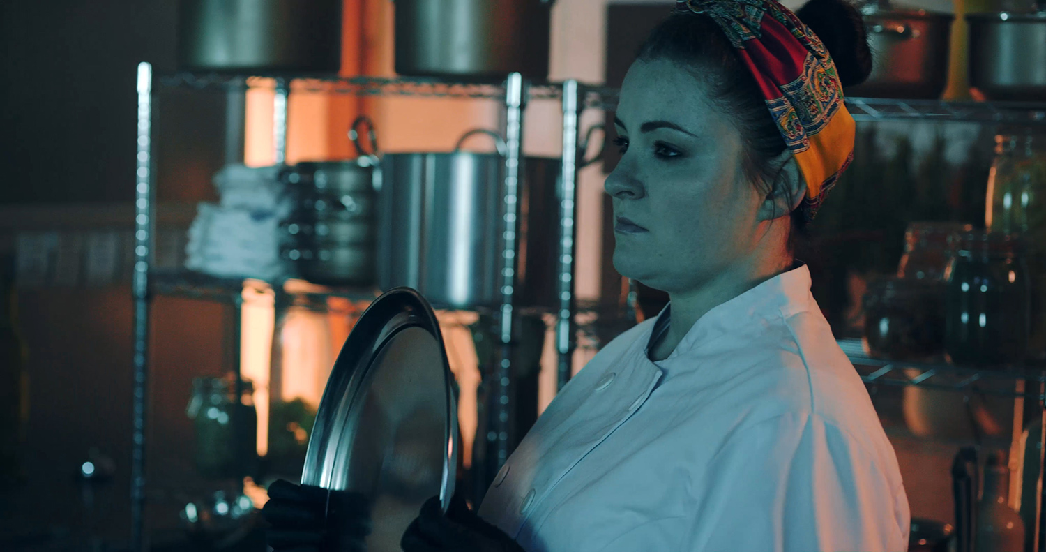 Belle (Charlie Drummond) holding a silver plate up to Angus's (Arthur Bruce's) face in The Narcissistic Fish